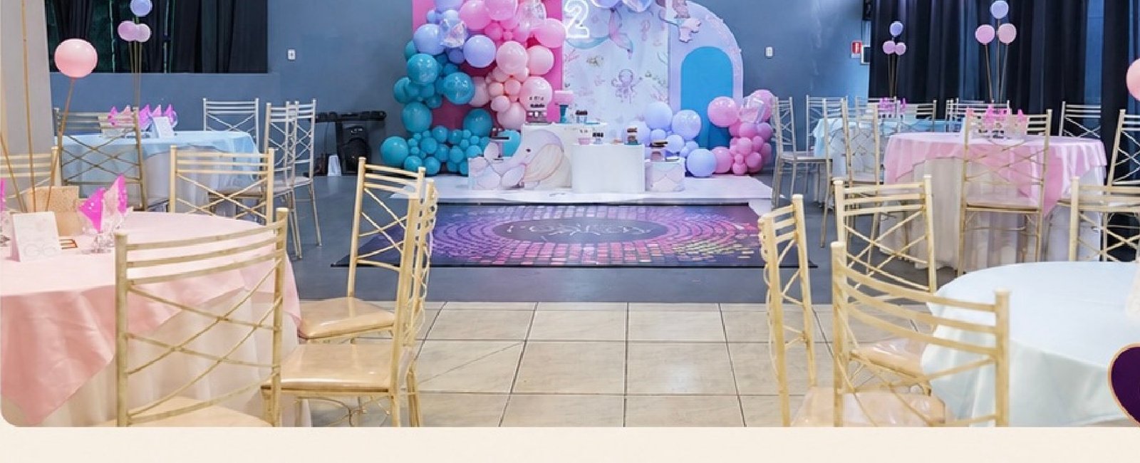 Salão da FesThay montado com mesas, cadeiras douradas e decoração em balões para uma festa