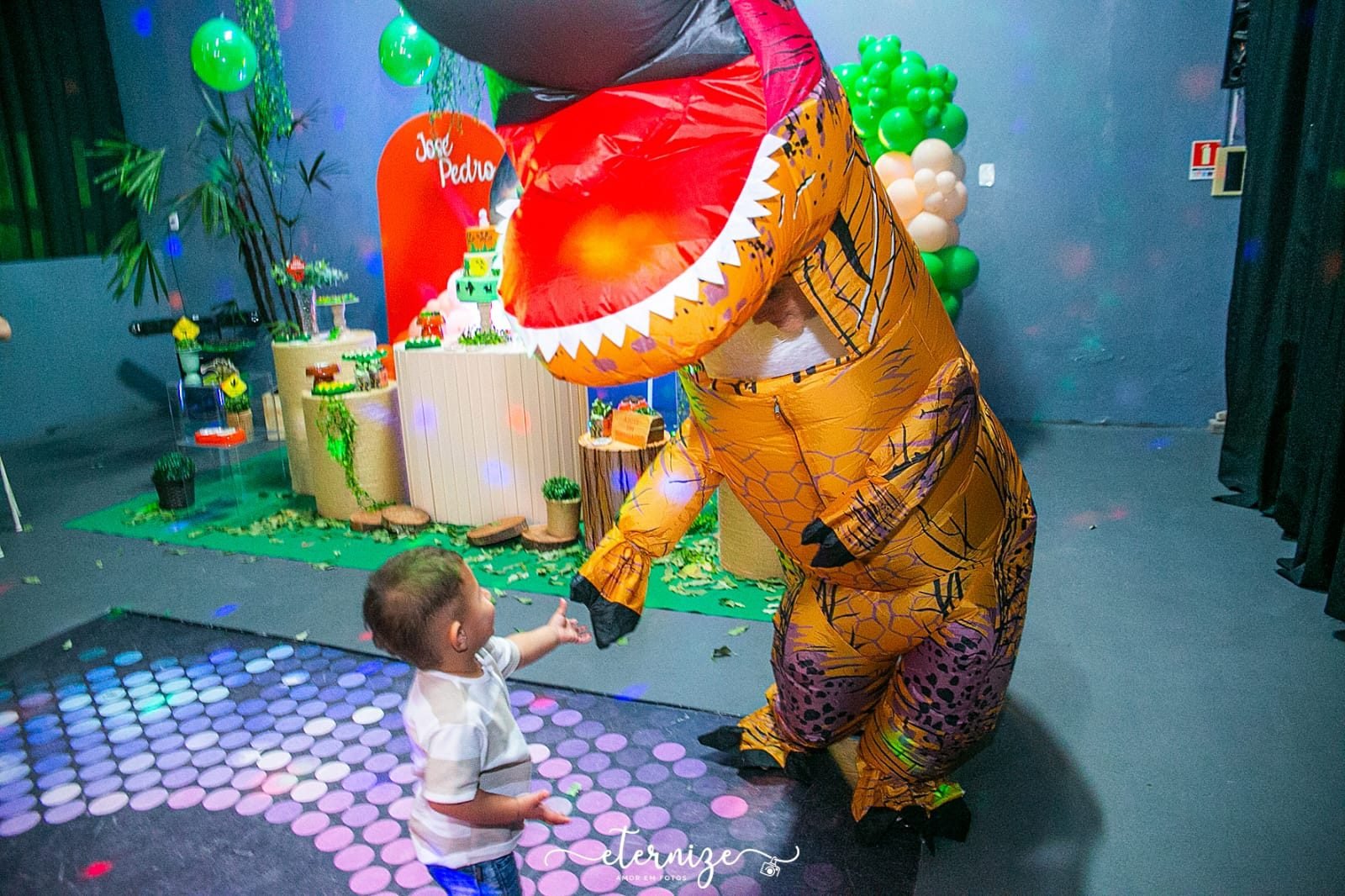 Personagem de dinossauro animando a criança na festa temática da FesThay