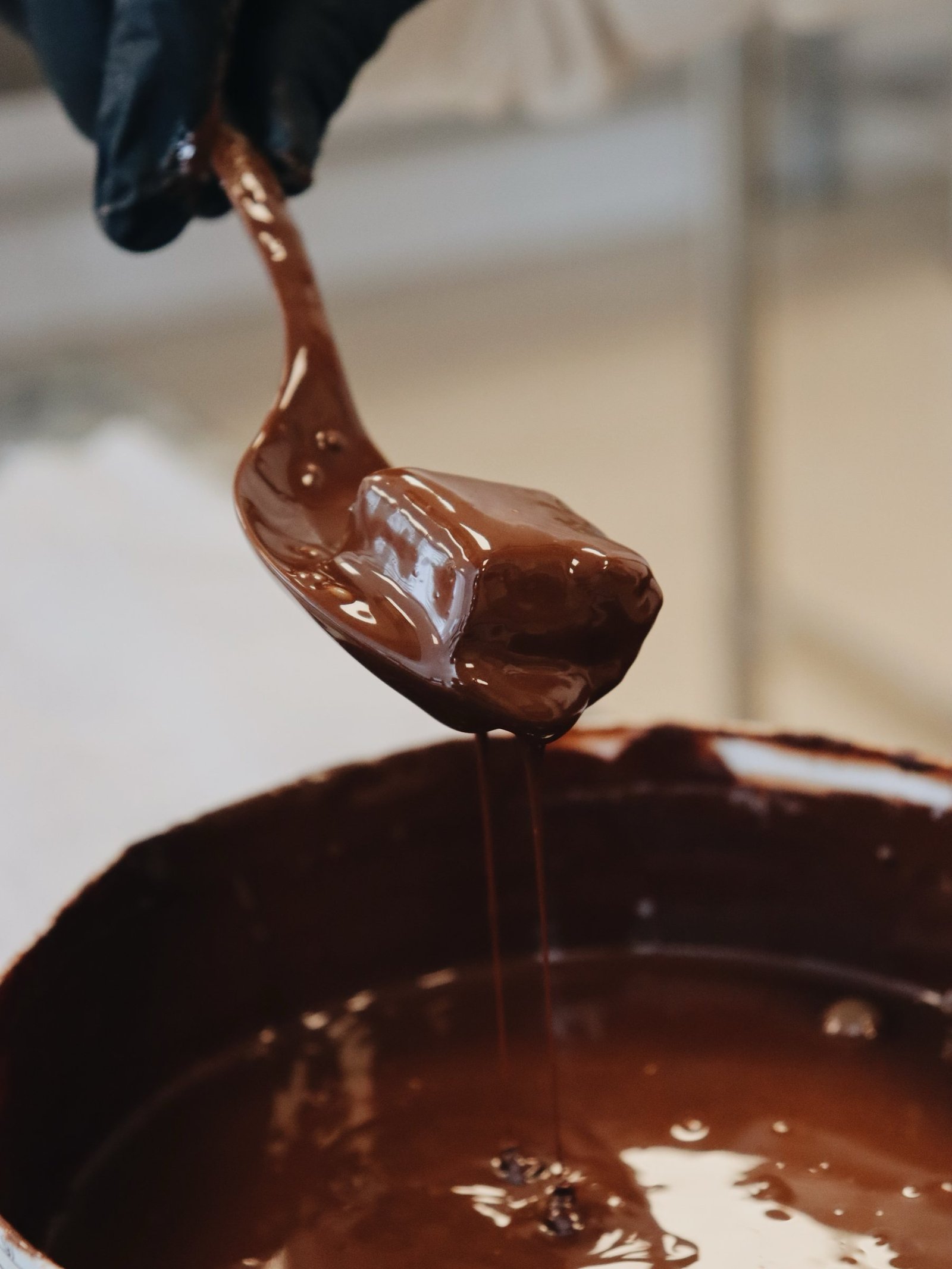 Chocolate temperado escorrendo da concha na cozinha da Ammo Brownie