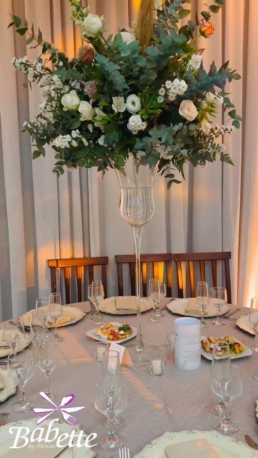 Mesa de evento decorada pela Babette, com arranjo floral alto, louça e taças