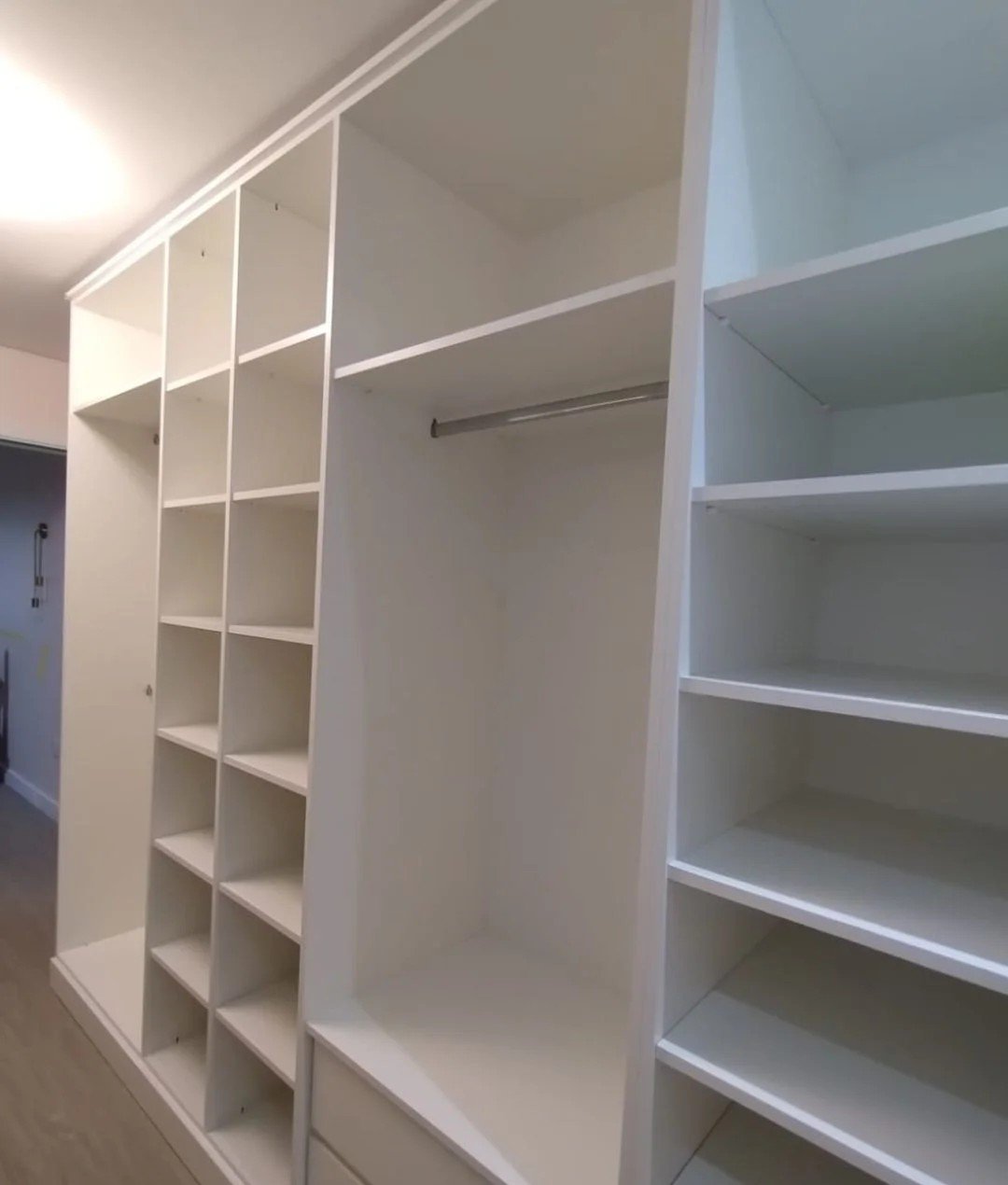 Closet planejado em L com colmeias, cabideiros e prateleiras