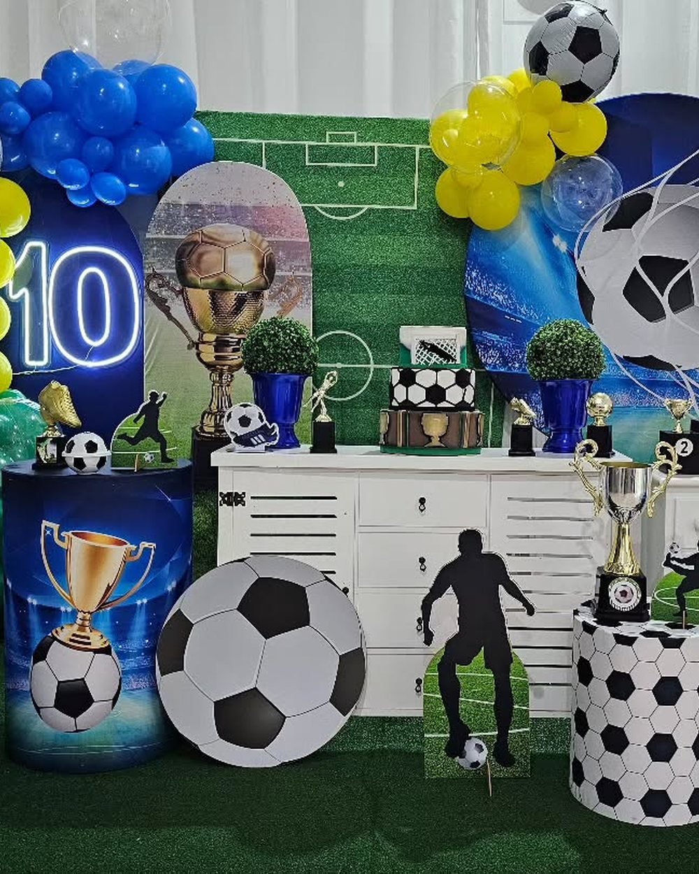 Decoração de festa tema futebol com balões azuis, bolas e troféus