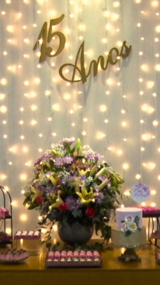 Mesa principal de 15 anos com letreiro dourado e arranjo de flores no Espaço 846